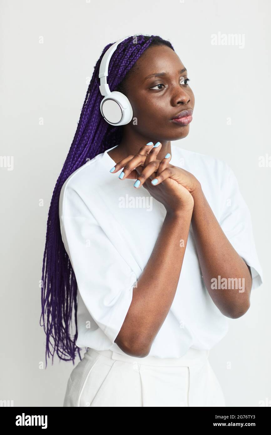 Ritratto minimo di una giovane donna afroamericana che indossa le cuffie su sfondo bianco Foto Stock