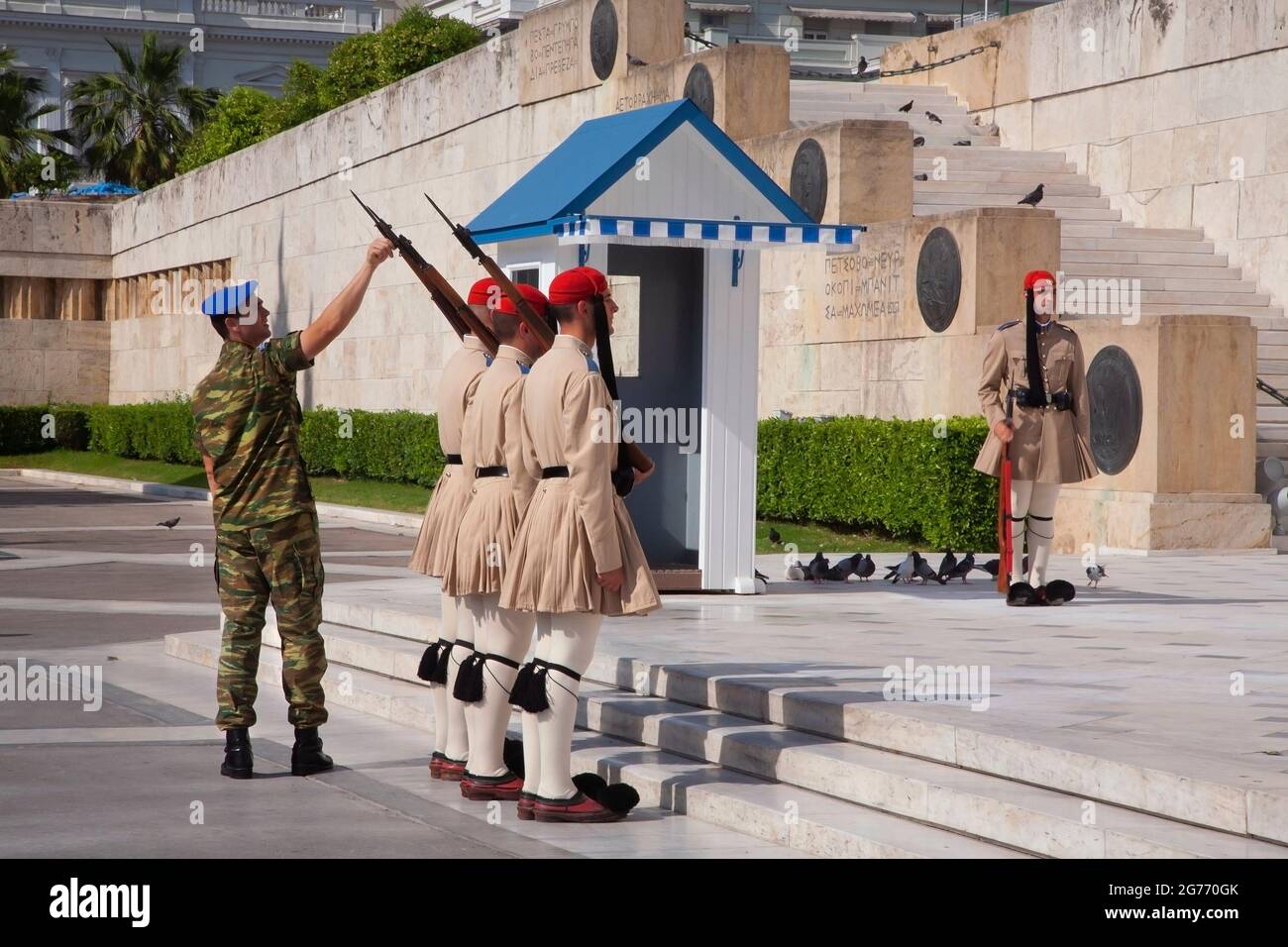 Solista che ispeziona gli evzone in uniforme estiva della guardia presidenziale al memoriale militare ai guerrieri caduti al Parlamento greco ad Atene Foto Stock