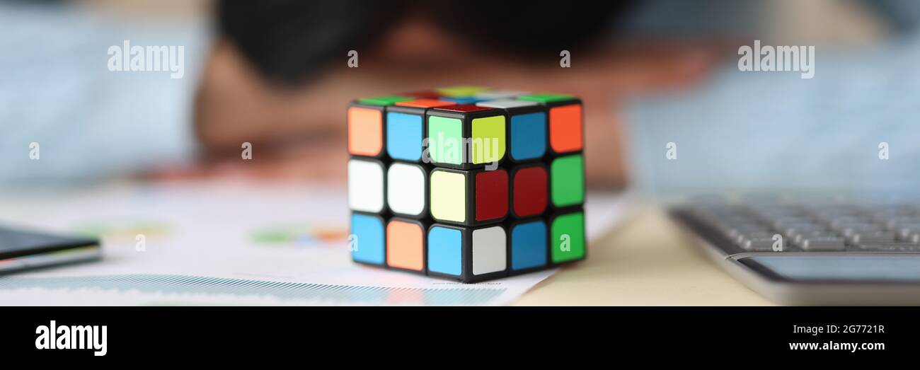 Rubik è cubo sul tavolo con donna stanca in background Foto Stock