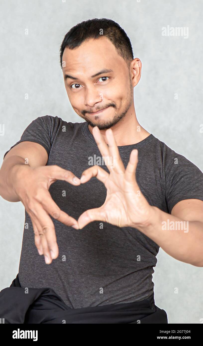 Gli uomini attraenti sono innamorati di hands.A a forma di cuore un sorriso che è speciale, diverso, è la testa e la faccia del focus.close-up Foto Stock