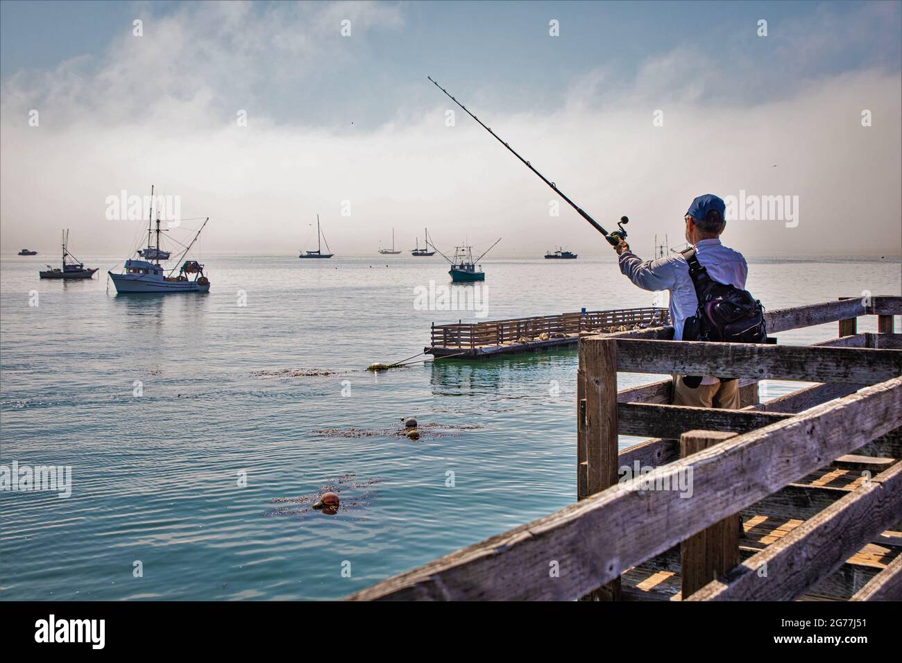 Uomo pescatore pesca dal vecchio molo in California la mattina presto come  la nebbia si solleva con il suo zaino e palo sul litorale pacifico Foto  stock - Alamy