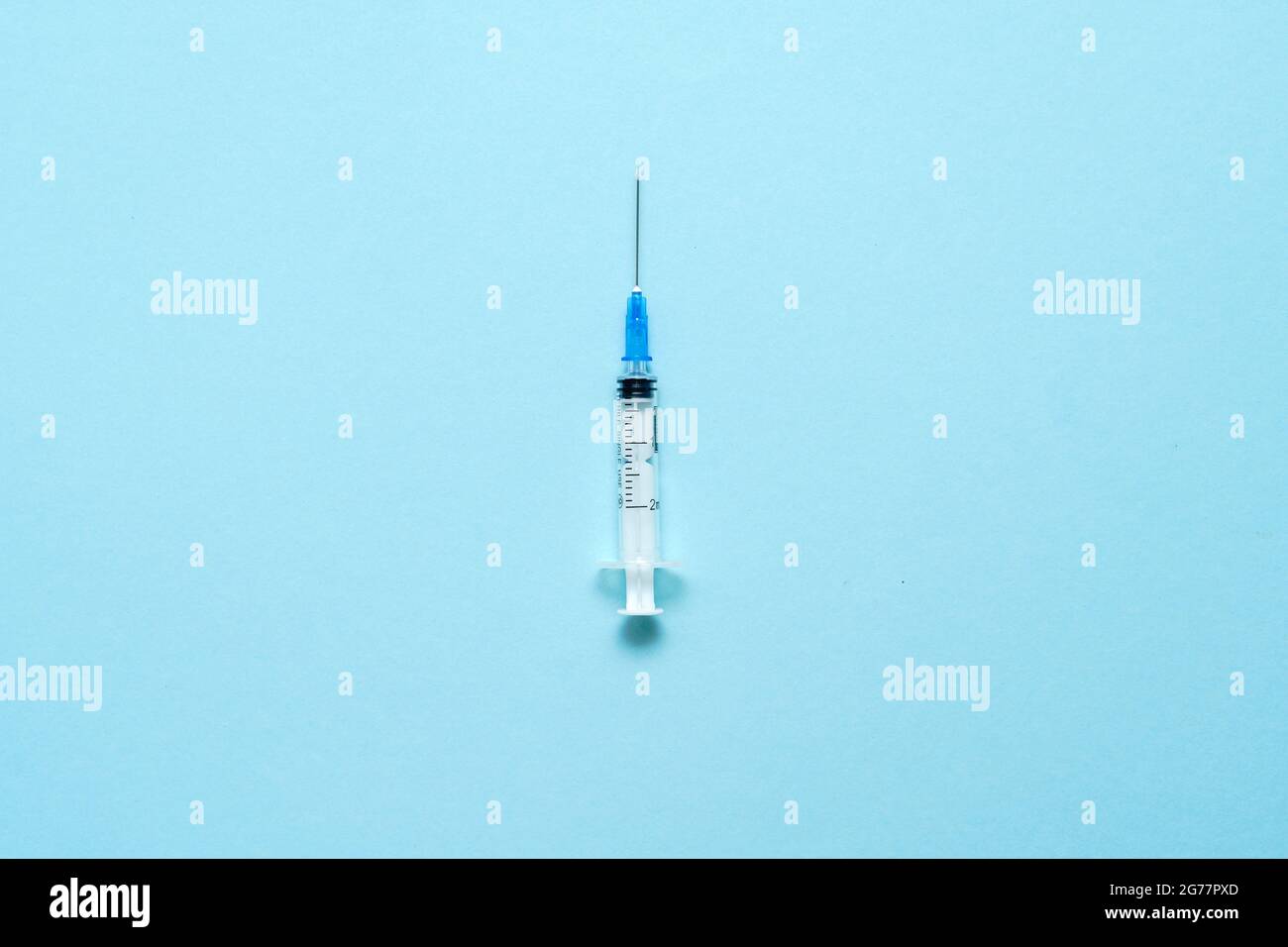 Vista dall'alto della siringa per iniezione su sfondo blu. Concetto minimo di vaccino. Trattamento medico del diabete con insulina. Vaccinazione di Covid-19. Antivax Foto Stock