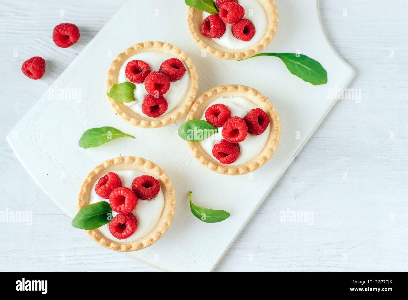 Tartine con panna e lampone su tavola di legno bianco Foto Stock