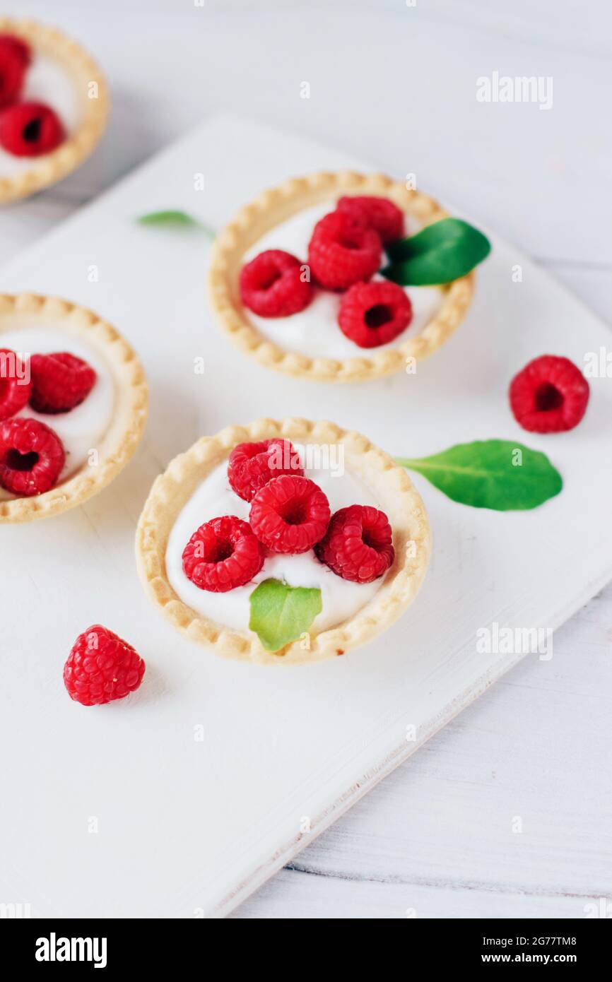Tartine con panna e lampone su tavola di legno bianco Foto Stock