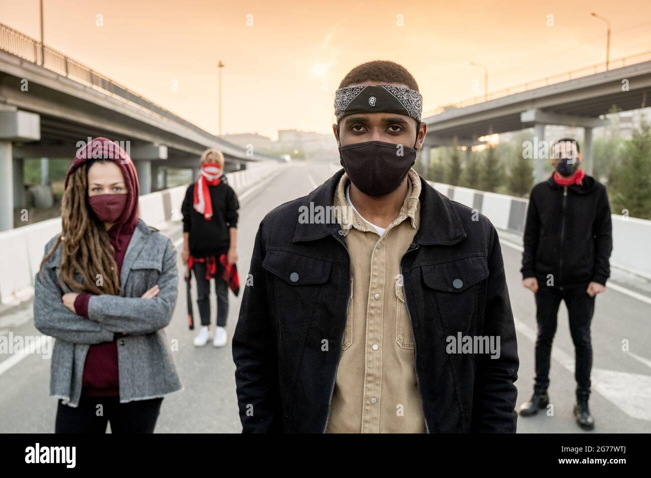Gruppo di giovani dispiaciuti multietnici in abbigliamento casualwear che si spostano per strada mentre rivendicano i loro diritti Foto Stock