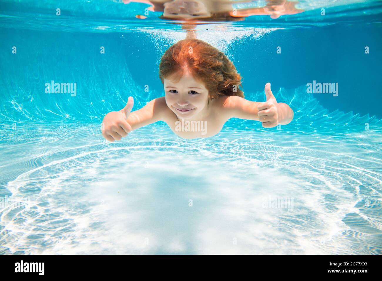 I bambini nuotano sott'acqua in piscina. Bambino ragazzo che nuota sotto  l'acqua con i pollici in su Foto stock - Alamy