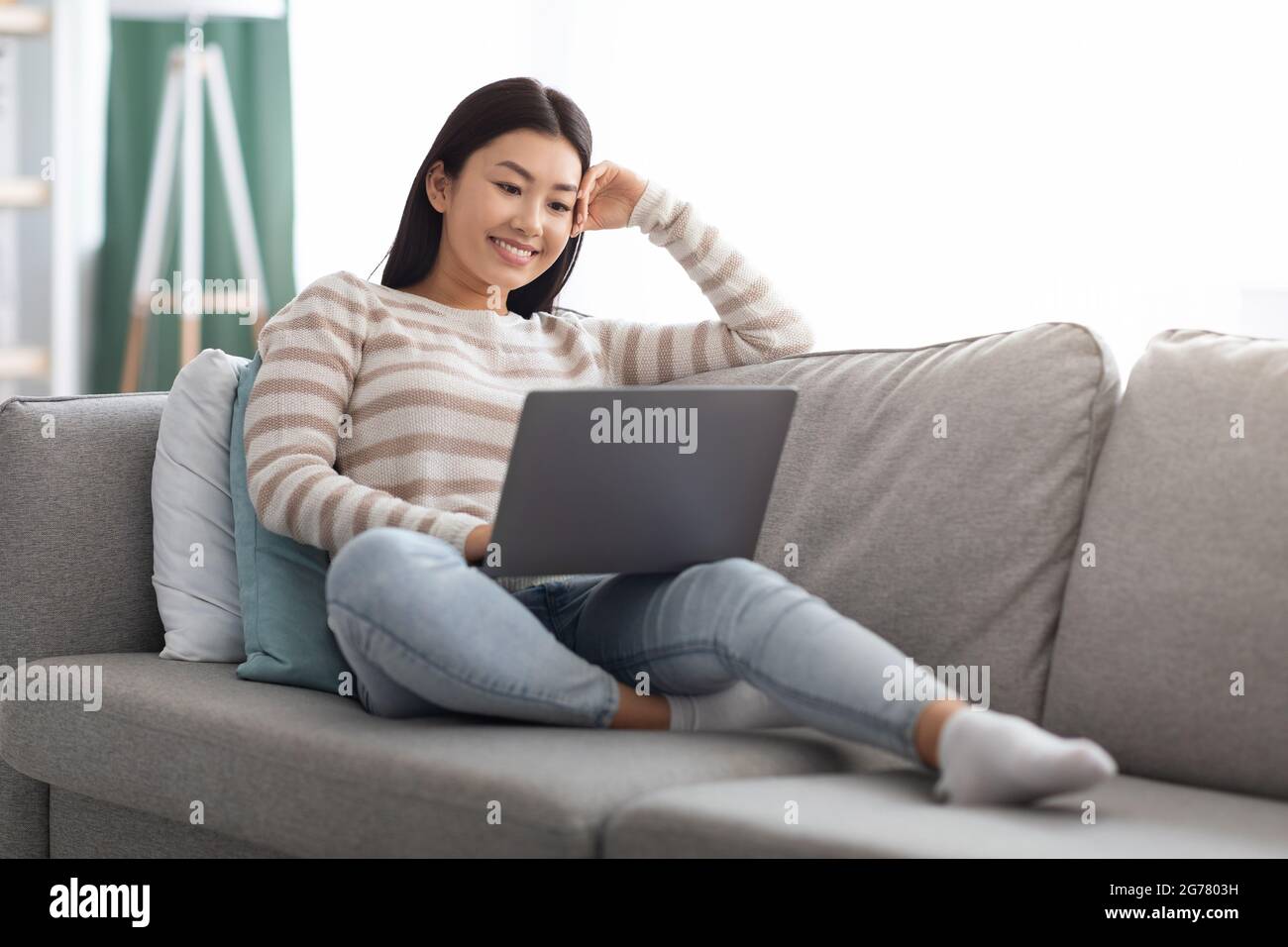 Happy Young Asian Woman guardando i film on-line sul laptop a casa Foto Stock