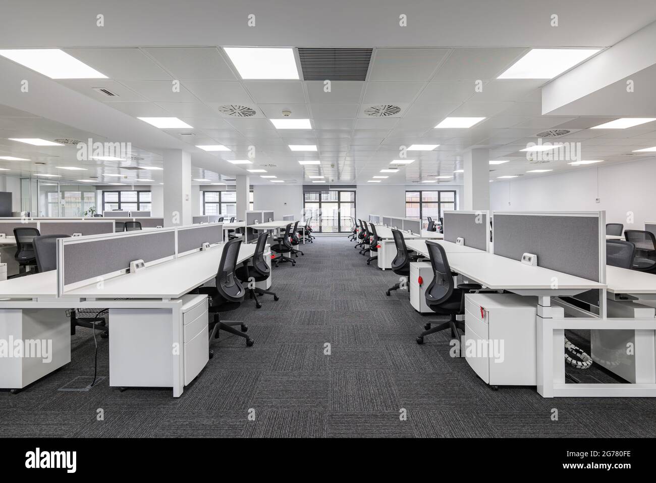 Moderno ufficio aziendale aperto dal design minimalista e moderno in bianco e grigio, postazioni di lavoro vuote per ufficio. Foto Stock