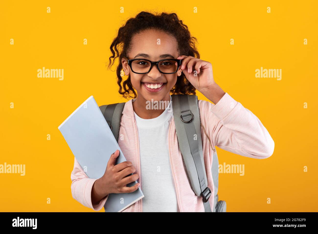 Giovane ragazza nera sicura che tiene libri di testo guardando la macchina fotografica Foto Stock