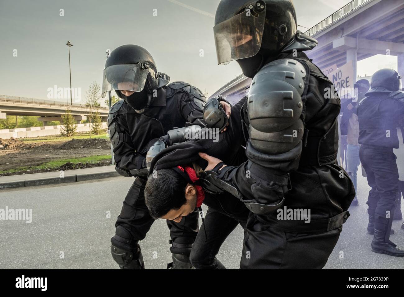 Abili poliziotti in caschi che tengono le mani di ribelli dietro la schiena mentre arrestano le persone al rally Foto Stock