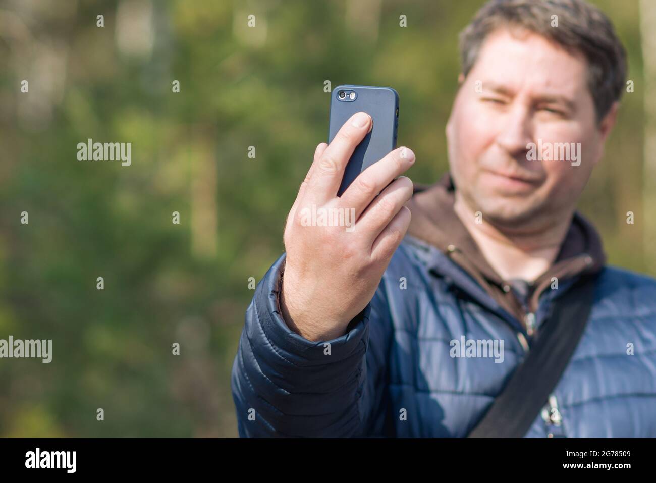 Un uomo di 40 anni con il suo smartphone cellulare alla ricerca del segnale di ricezione nella foresta primaverile. Foto Stock