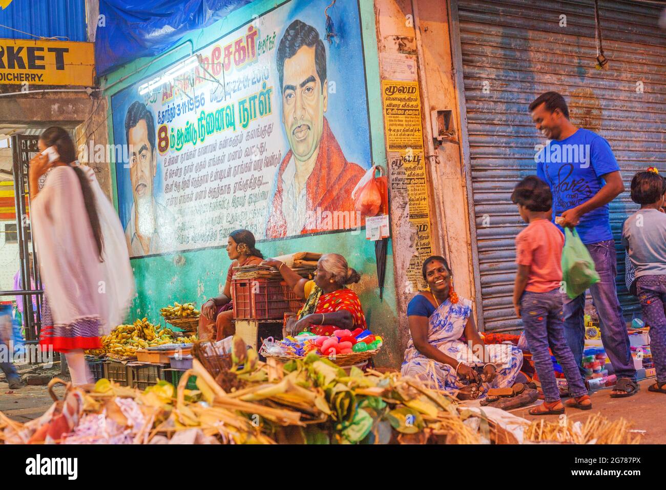 Il padre indiano ripartisce scherzo con il commerciante del mercato vegetale sotto le illustrazioni dipinte a mano colorate, Puducherry (Pondicherry), Tamil Nadu, India Foto Stock