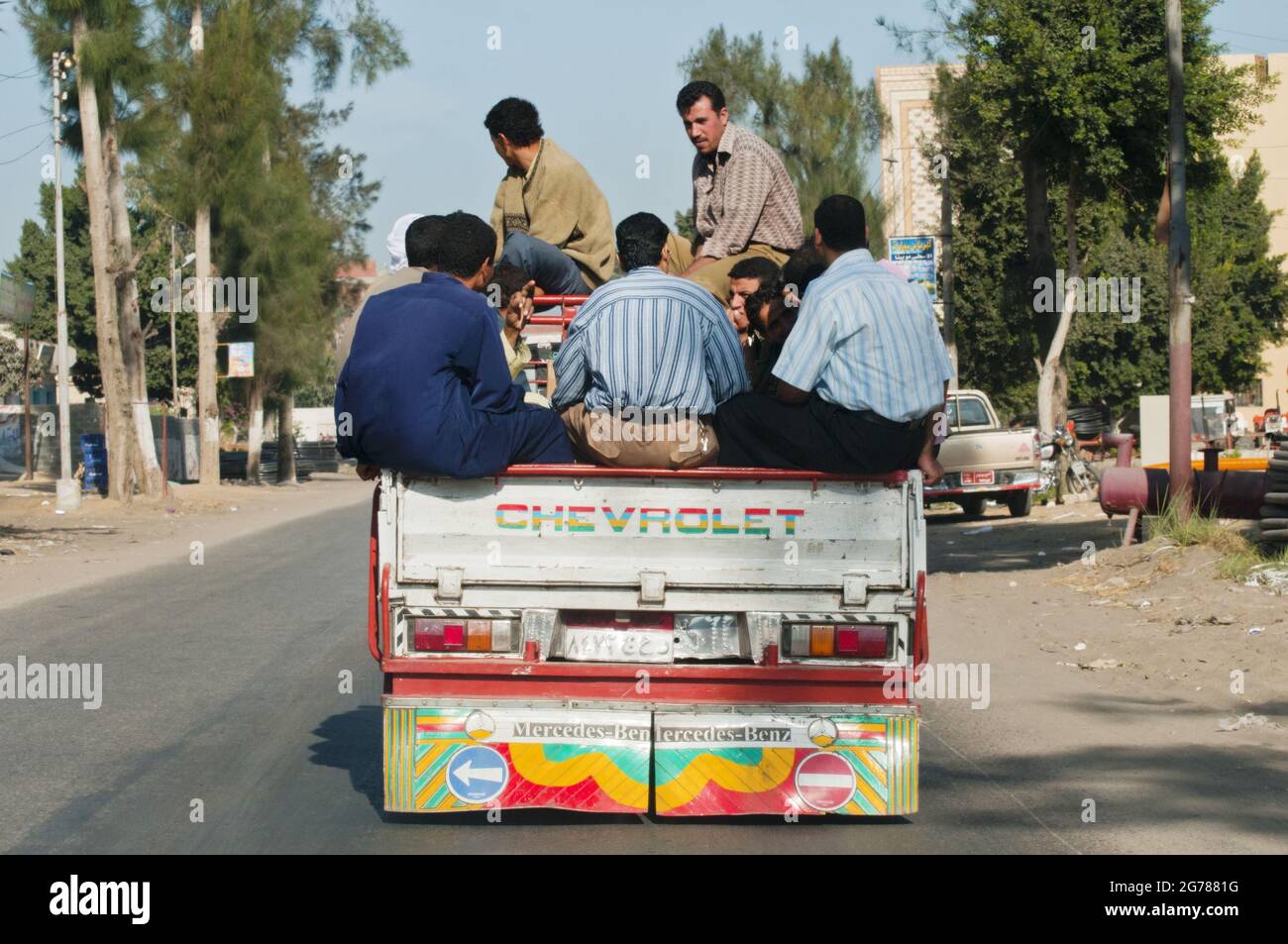 Uomini schiacciati in un giro in camion di pickup attraverso una città provinciale nel delta del Nilo, Egitto Foto Stock
