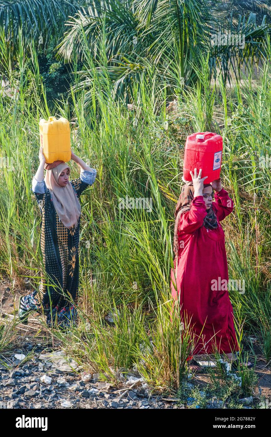 Due donne rurali riportano l'acqua alle loro case nel delta del Nilo, in Egitto Foto Stock