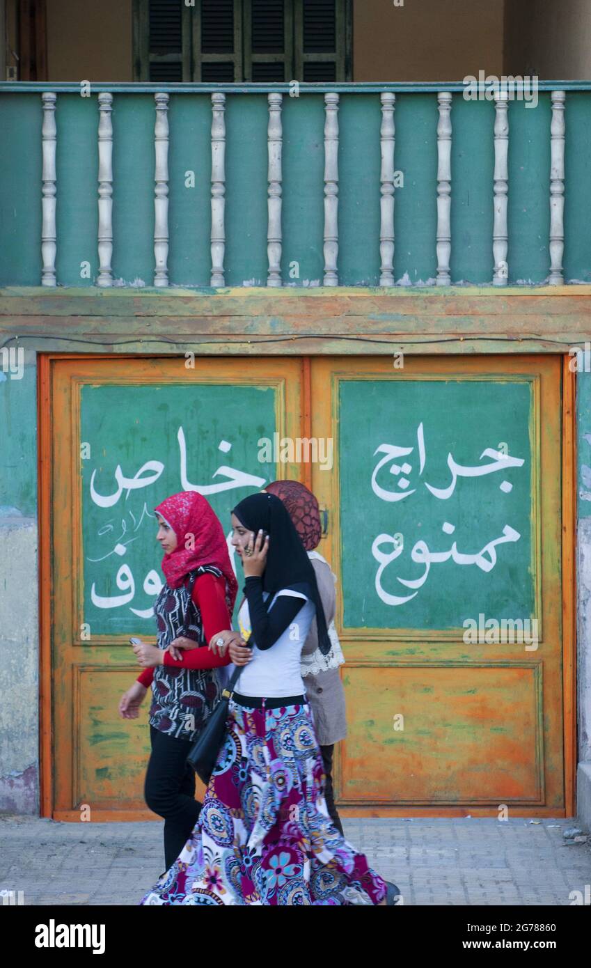 Scena di strada come un gruppo di giovani donne passa una porta ad Alessandria, Egitto Foto Stock