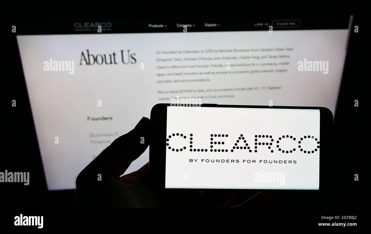 Persona che detiene smartphone con il logo della società finanziaria americana Clearco sullo schermo di fronte al sito Web. Mettere a fuoco il display del telefono. Foto Stock
