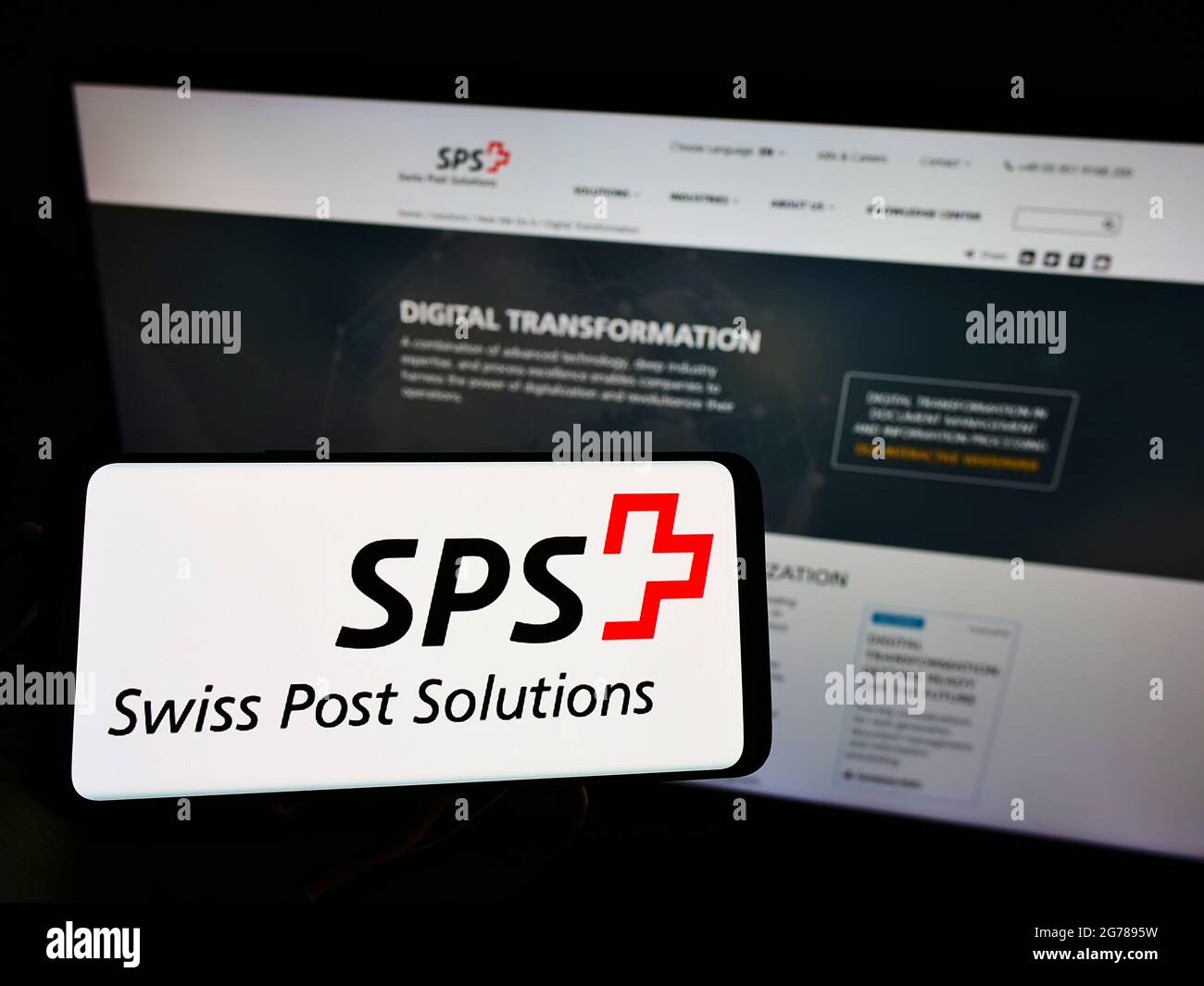 Persona che detiene il cellulare con il logo della società di gestione documenti Swiss Post Solutions (SPS) sullo schermo davanti alla pagina web. Mettere a fuoco il display del telefono. Foto Stock