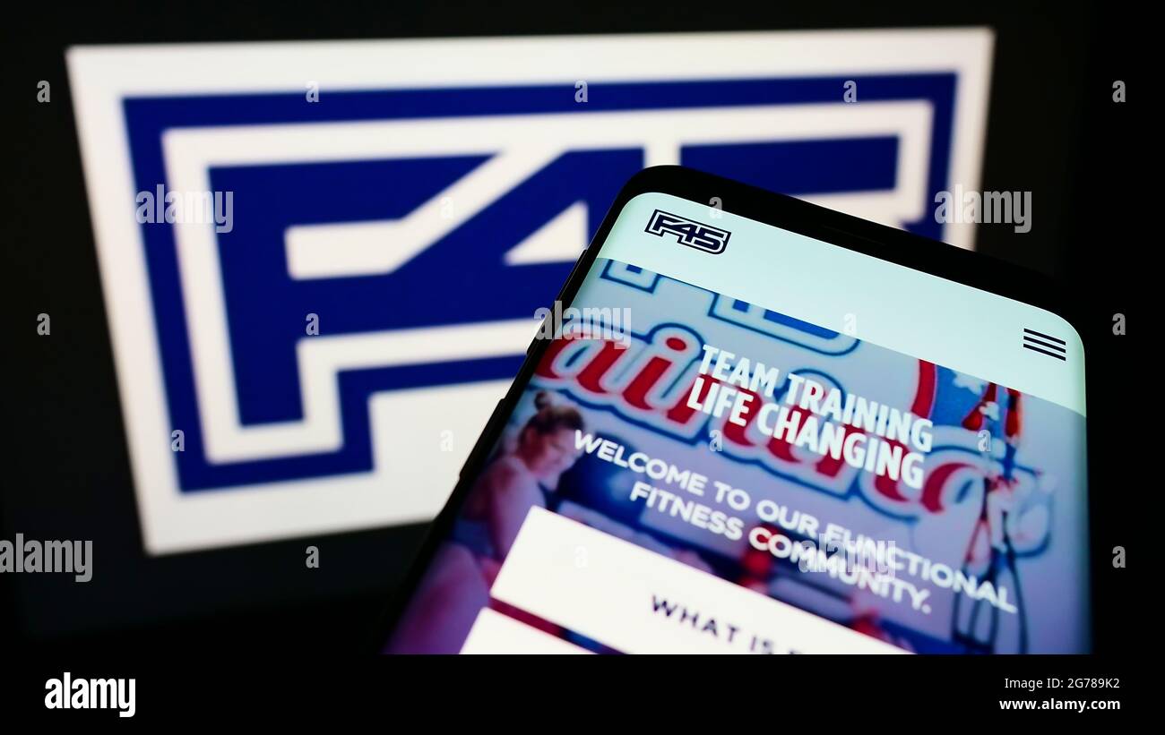 Telefono cellulare con pagina web della società di fitness F45 Training Holdings Inc. Sullo schermo davanti al logo aziendale. Mettere a fuoco in alto a sinistra del display del telefono. Foto Stock