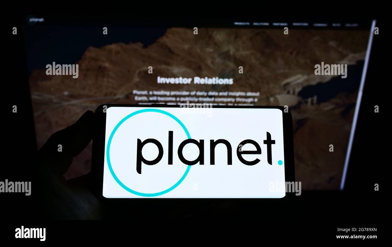 Persona che tiene lo smartphone con il logo della società di imaging terrestre statunitense Planet Labs Inc. Sullo schermo davanti al sito Web. Mettere a fuoco il display del telefono. Foto Stock