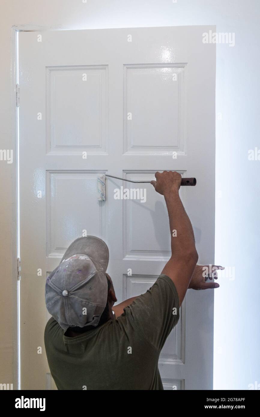 Persona che dipinge porta bianca di legno con rullo di vernice durante la  rinovazione domestica Foto stock - Alamy