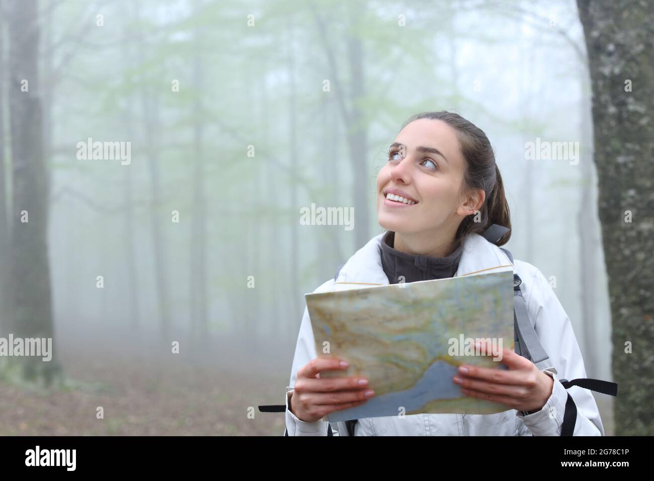 Happy Trekker tenendo carta mappa guardando a lato in natura un giorno foggy Foto Stock