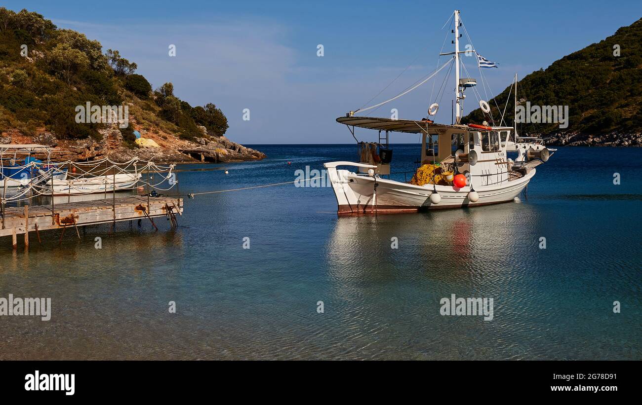 Isole IONIE, Ithaka, isola di Odysseus, vicino a Vathi, Sarakiniko Beach, barche, barche a vela, blu acqua, verde e turchese, dream bay, cielo blu, parte di un molo a sinistra nella foto, barca da pesca a destra nella foto Foto Stock