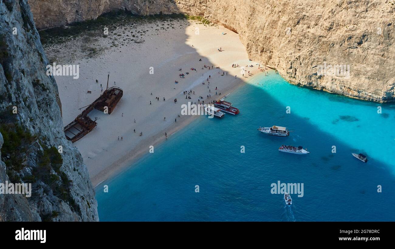 Zakynthos, Paralia Navagio, Shipwreck Beach, vista dall'alto nella baia e la spiaggia, relitto della MV Panagiotis, folla di persone sulla spiaggia, molte escursioni in barca all'ancora, acque turchesi Foto Stock