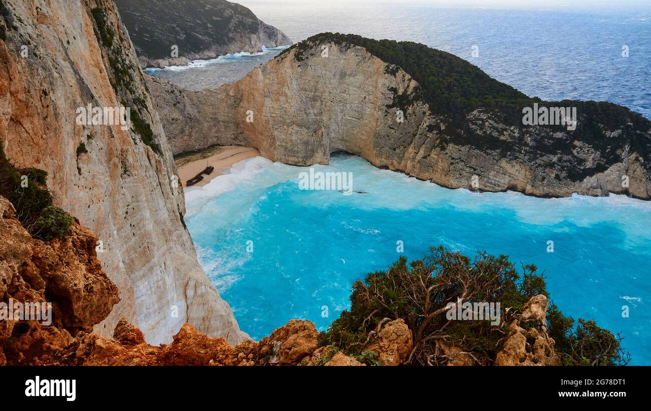 Zakynthos, Paralia Navagio, Shipwreck Beach, vista dall'alto su tutta la baia e parte della spiaggia, relitto MV Panagiotis, mari pesanti, onde che rotolano sulla spiaggia, acque turchesi, rocce in primo piano Foto Stock