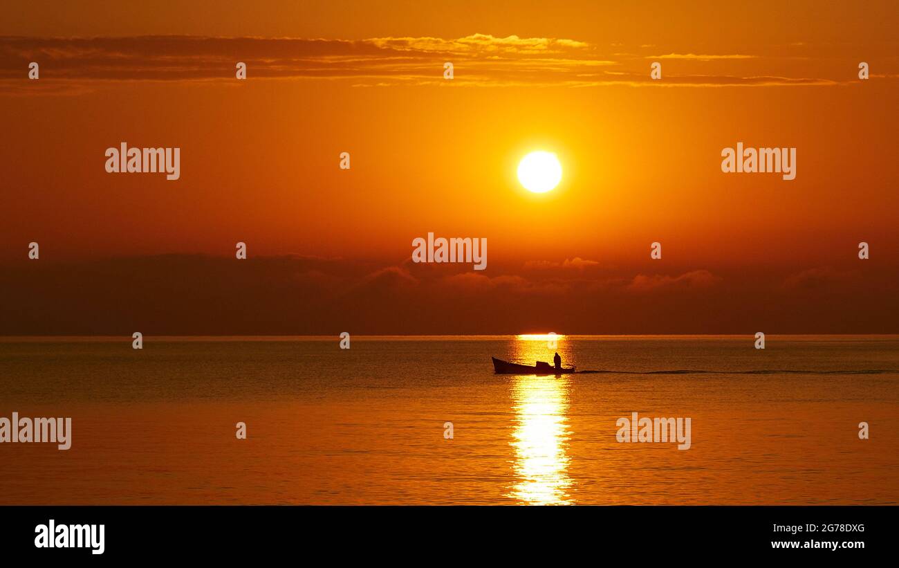 Zante, città di Zante, luce del mattino, umore del mattino, alba sopra la barca da pesca nel raggio del sole, cielo arancione, nuvole sparse Foto Stock