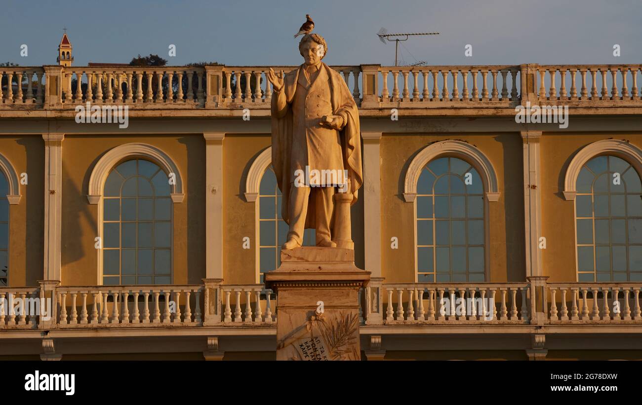 Zante, città di Zante, Piazza Solomos, statua del poeta nazionale Dionisios Solomos di fronte al Museo bizantino della città di Zante, sullo sfondo quattro finestre ad arco del Museo bizantino, piccione siede sulla testa della statua, luce del mattino, stretta striscia di cielo azzurro sul museo e la statua Foto Stock