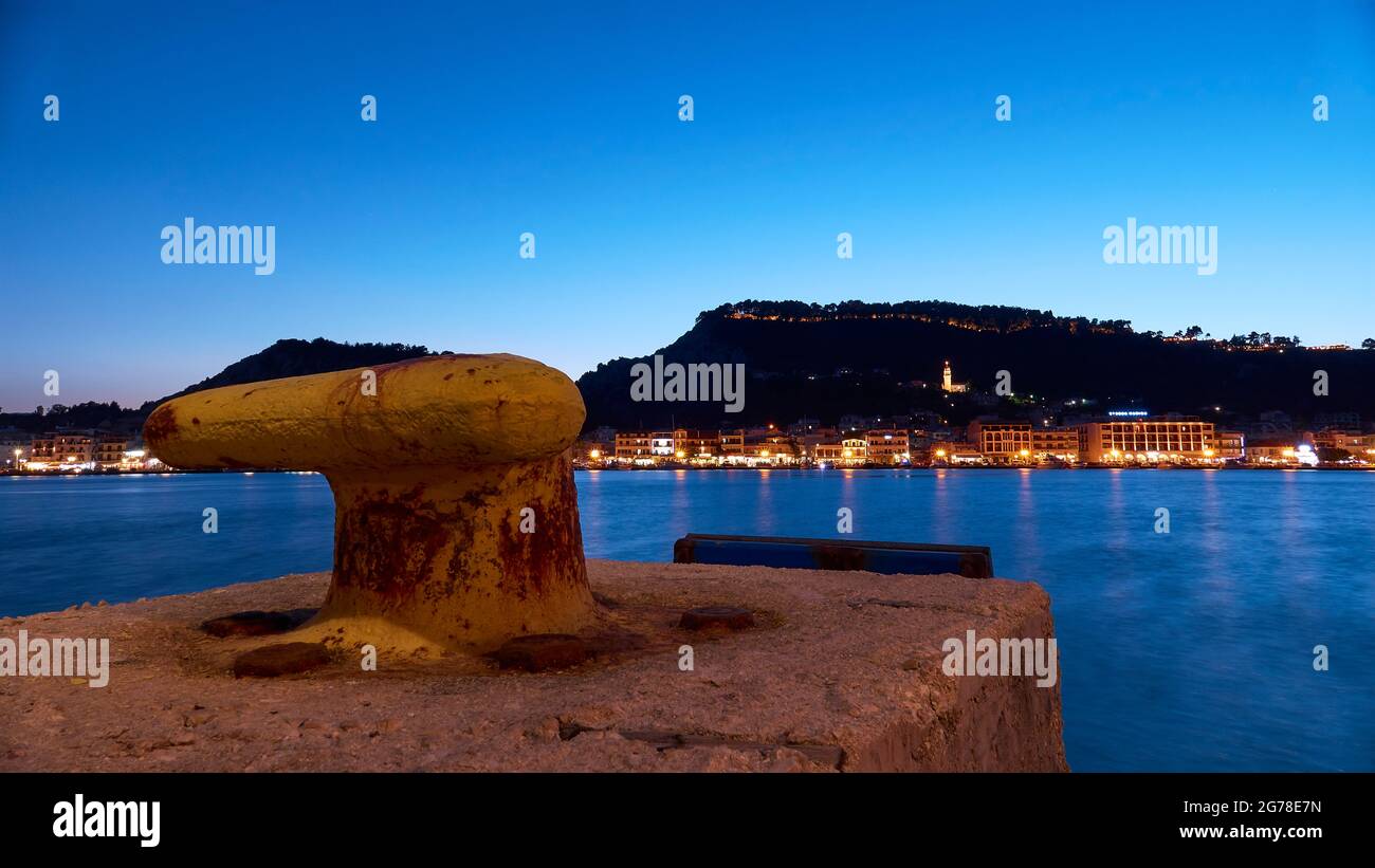 Zante, città di Zante, tiro notturno, tiro serale, porto, Molo giallo in primo piano, skyline notturno della città di Zante a metà distanza, collina del castello sullo sfondo, cielo notturno blu, torre illuminata della chiesa di Agias Triadas Foto Stock