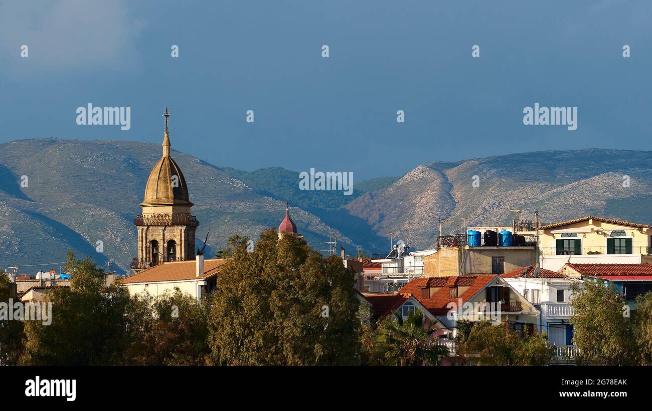 Zante, città di Zante, vista delle case e della torre della chiesa, montagne sullo sfondo, cielo blu, nuvole chiare Foto Stock