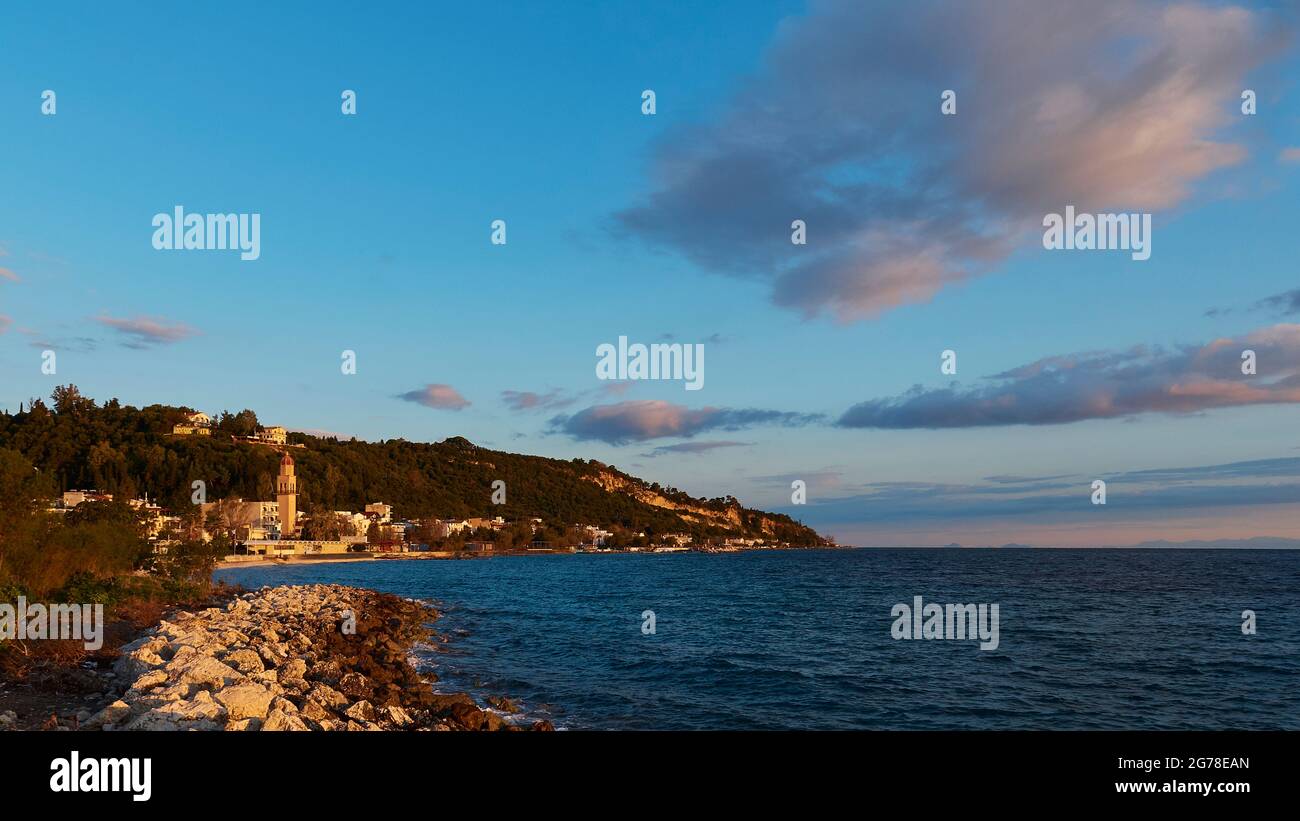 Zakynthos, Zakynthos City, luce del mattino, vista del nord-est della città attraverso il mare, Chiesa di Agias Triadas (Santa Trinità), riva sassosa, cielo blu, nuvole grigio-bianco Foto Stock
