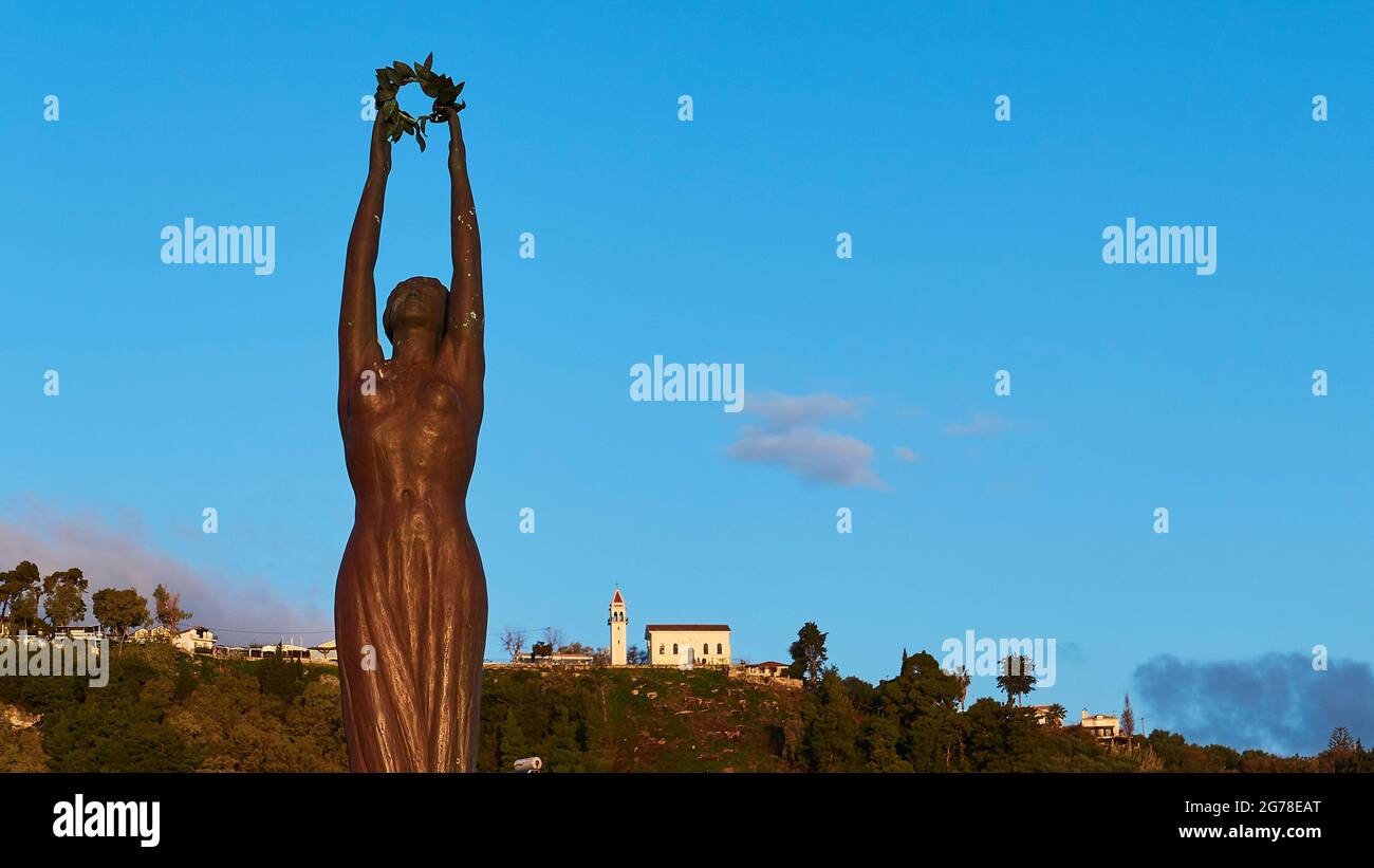 Zante, Zante, Piazza Solomos, Statua della libertà in bronzo, cielo blu, luce del mattino, nuvole singole, chiesa sulla collina sullo sfondo Foto Stock