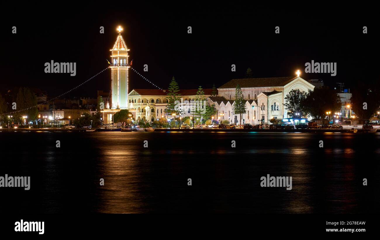 Zante, città di Zante, girata notturna, girata serale, chiesa di Agios Dionisios, illuminata in modo festivo, torre della chiesa getta riflessi di luce sull'acqua oscura Foto Stock