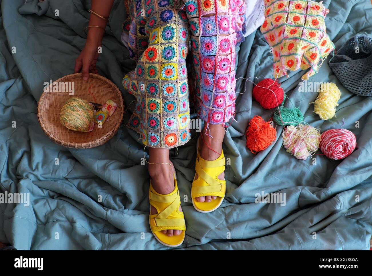 Vista dall'alto gambe donna con prodotto fatto a mano per caldo in inverno, coperta colorata crocheted da link molti pezzi d'arte per fare belle forme grafiche f Foto Stock