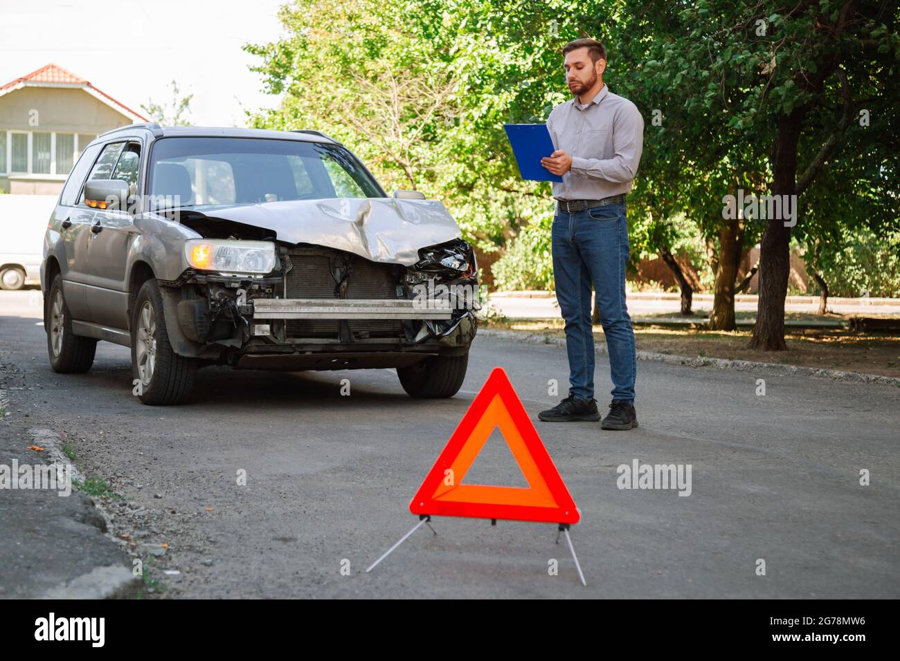 L'assicuratore ispeziona l'auto e calcola i danni dopo un incidente. Agente assicurativo MAN Auto controllare le condizioni di danneggiamento del veicolo. Auto rotta su strada con Red Foto Stock