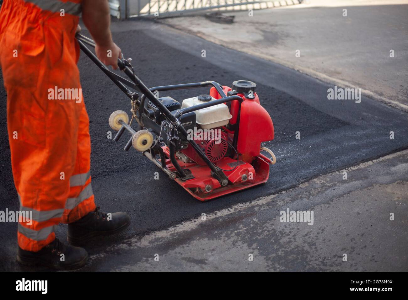 Posa di asfalto. Livellamento della strada. Un lavoratore comprime asfalto  caldo. Riparazione della superficie stradale Foto stock - Alamy