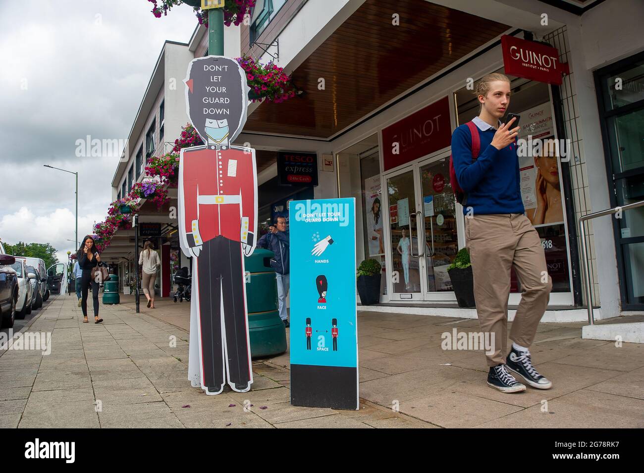 Ascot, Berkshire, Regno Unito. 12 luglio 2021. Non lasciate che la vostra guardia giù avviso in Ascot High Street. Boris Johnson è tenuto a dare un briefing stampa questo pomeriggio, dove si prevede di sollevare il Covid-19 blocco compreso il requisito di indossare maschere nei negozi e sui mezzi di trasporto pubblico. Dato il picco enorme nei casi positivi di Covid-19, molta gente intende continuare a indossare le maschere del viso e a praticare la distanza sociale dopo il giorno della libertà il 19 luglio 2021 malgrado l'abolizione delle restrizioni. Credit: Maureen McLean/Alamy Live News Foto Stock