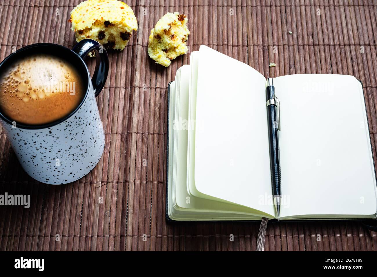 Taccuino vuoto con matita meccanica, muffin e tazza da caffè. Foto Stock