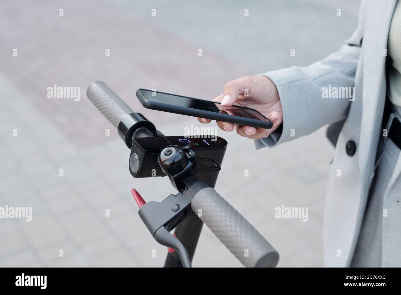 Mano di uomo d'affari con smartphone su tavolo tra le maniglie dello scooter Foto Stock