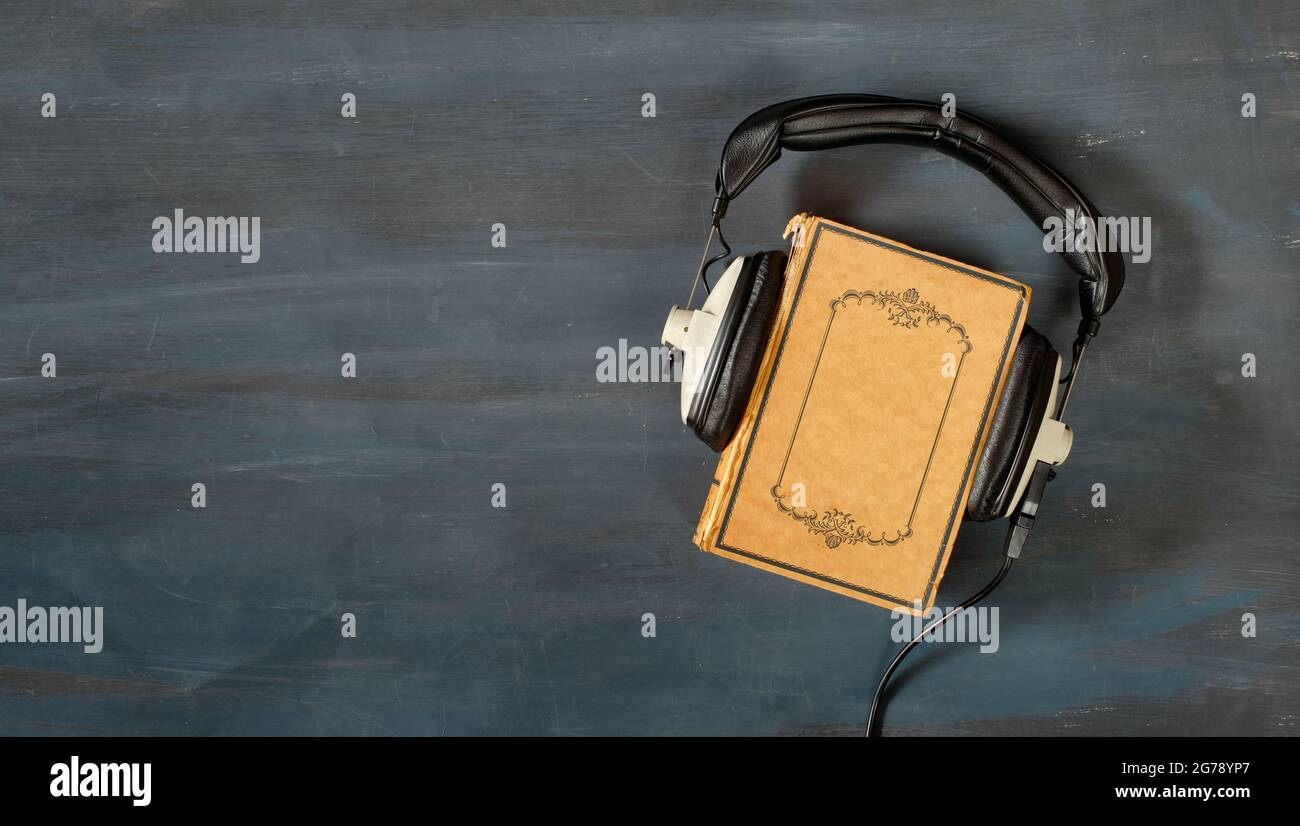 concetto di audiolibro con libro e cuffie vintage, letteratura, intrattenimento, istruzione, spazio di copia sulla copertina del libro Foto Stock