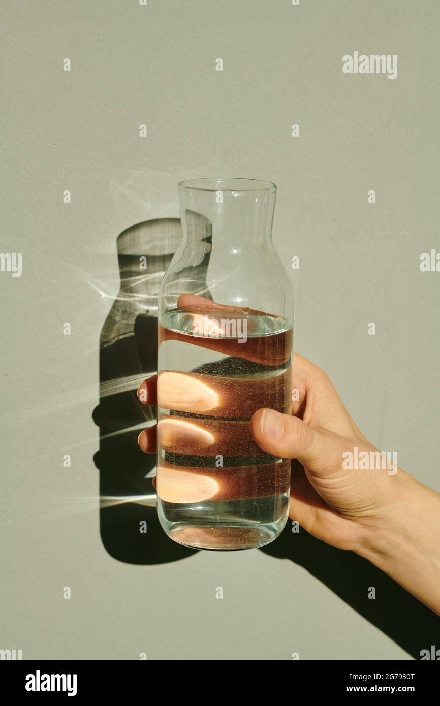 Mano di giovane femmina che tiene aperta bottiglia di acqua pura in isolamento Foto Stock