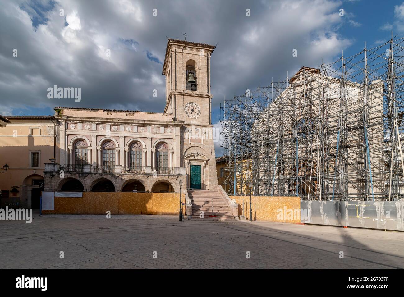 La facciata del Palazzo comunale di Norcia, Perugia, Italia, accanto alla basilica di San Benedetto, distrutta dal terremoto, sotto un cielo drammatico Foto Stock
