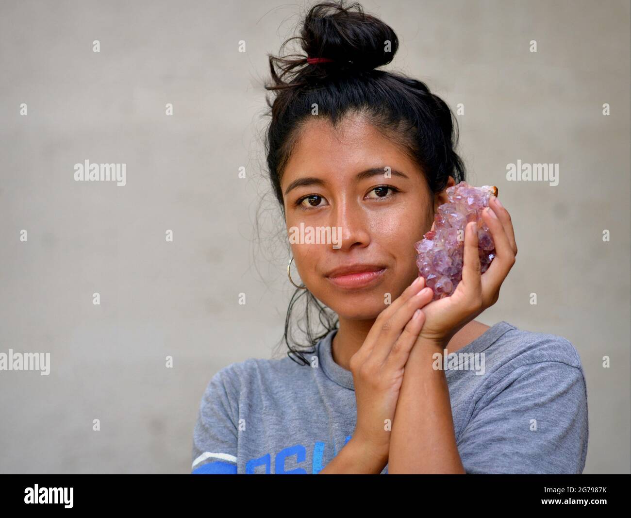 Giovane donna messicana tiene un grande e pesante cristallo con potere di guarigione in entrambe le mani e guarda spettatore. Foto Stock