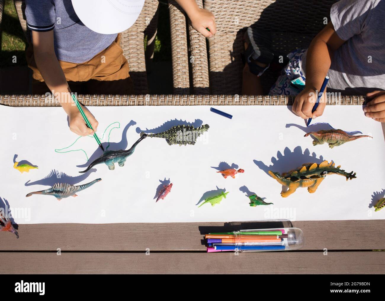 i bambini disegnano ombre contrastanti dai dinosauri giocattolo con una penna a punta di feltro. idee per la creatività dei bambini. Attività interessanti per i bambini a casa A. Foto Stock