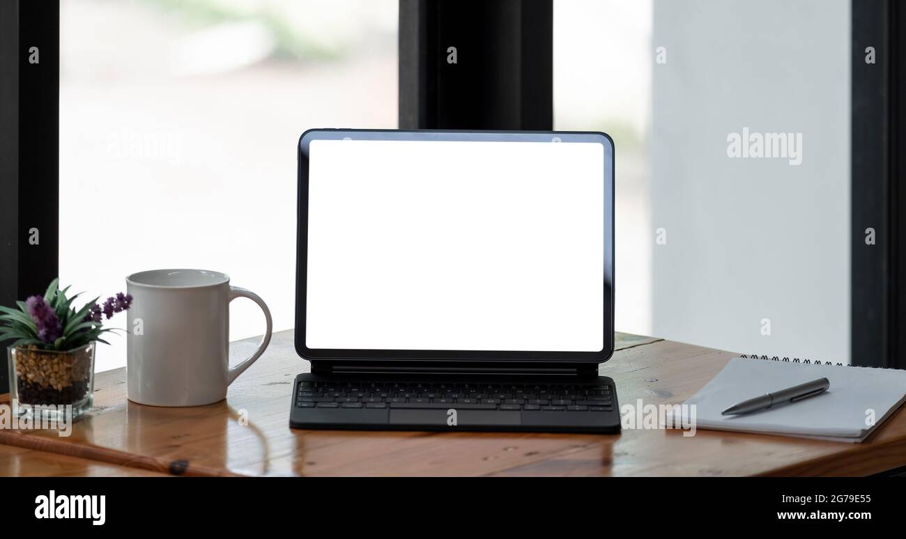 Immagine ritagliata di un tablet a schermo vuoto e di materiali per l'ufficio in un'area di lavoro semplice. Percorso di ritaglio Foto Stock