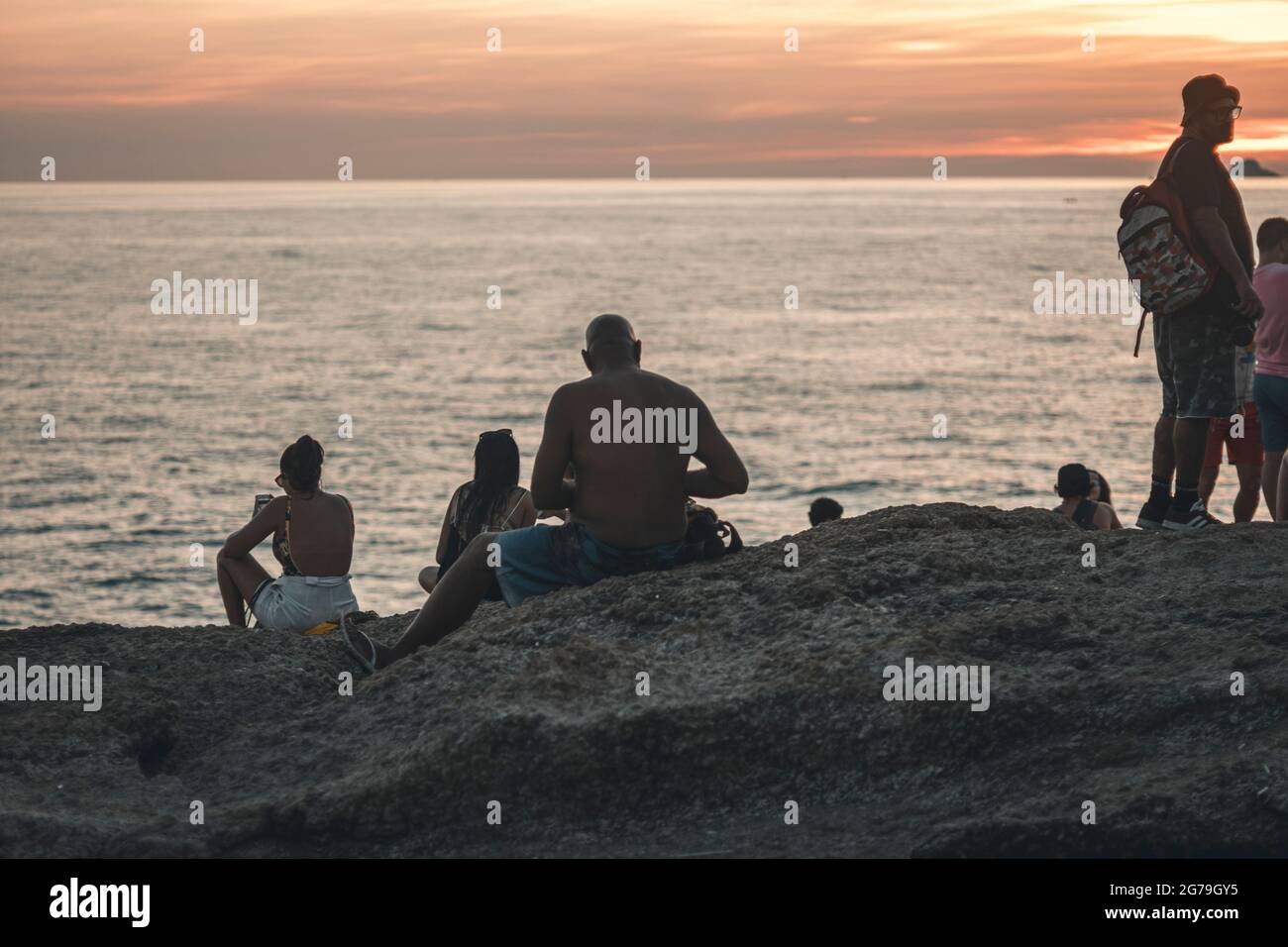 Un luogo magico: La gente applaude quando il sole tramonta alla roccia di Arpoador con vista della spiaggia di Ipanema e le montagne di Morro Dois Irmaos e Leblon nella parte posteriore. Macchina fotografica: Leica M10 Foto Stock