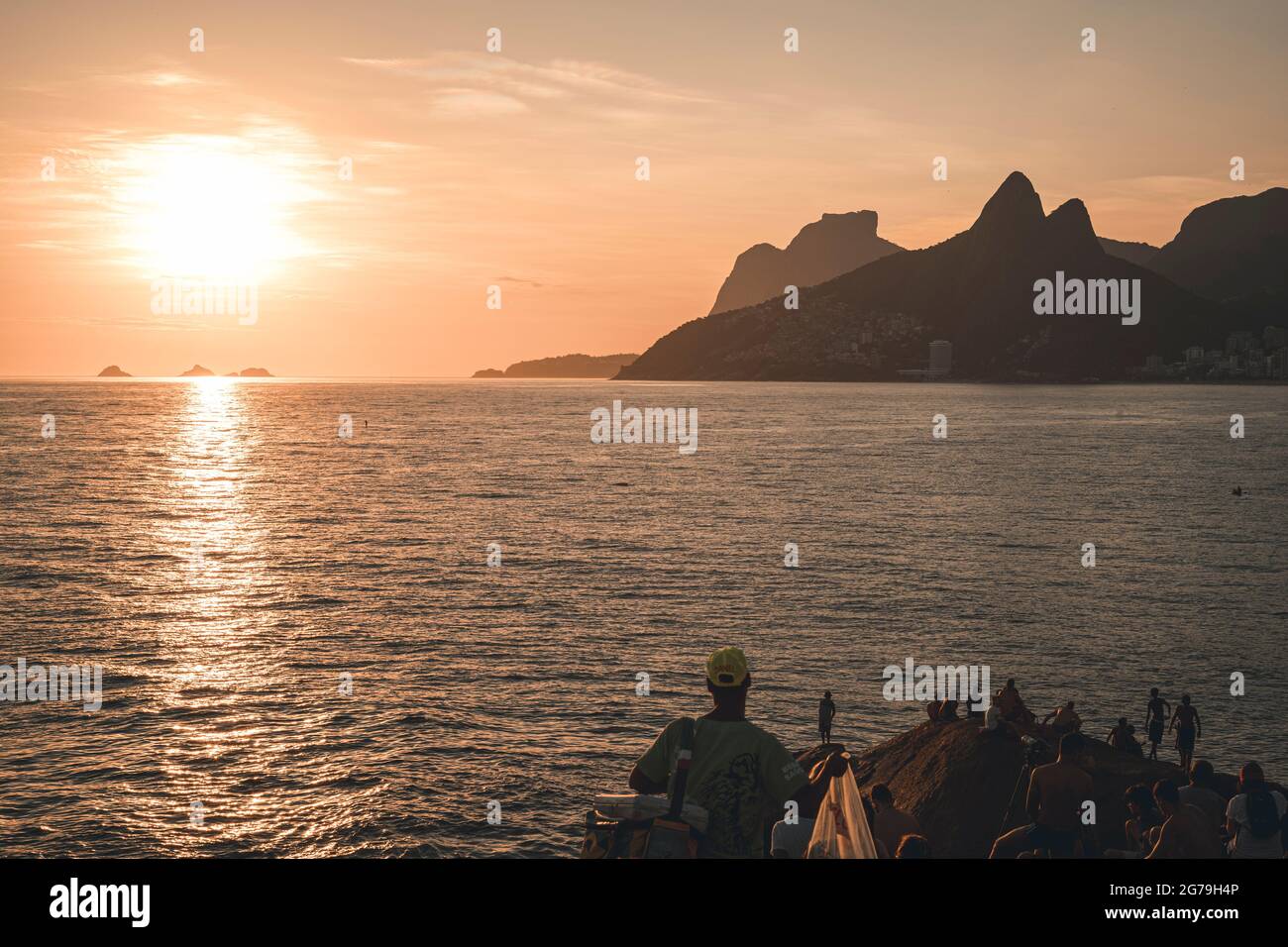 Un luogo magico: La gente applaude quando il sole tramonta alla roccia di Arpoador con vista della spiaggia di Ipanema e le montagne di Morro Dois Irmaos e Leblon nella parte posteriore. Macchina fotografica: Leica M10 Foto Stock