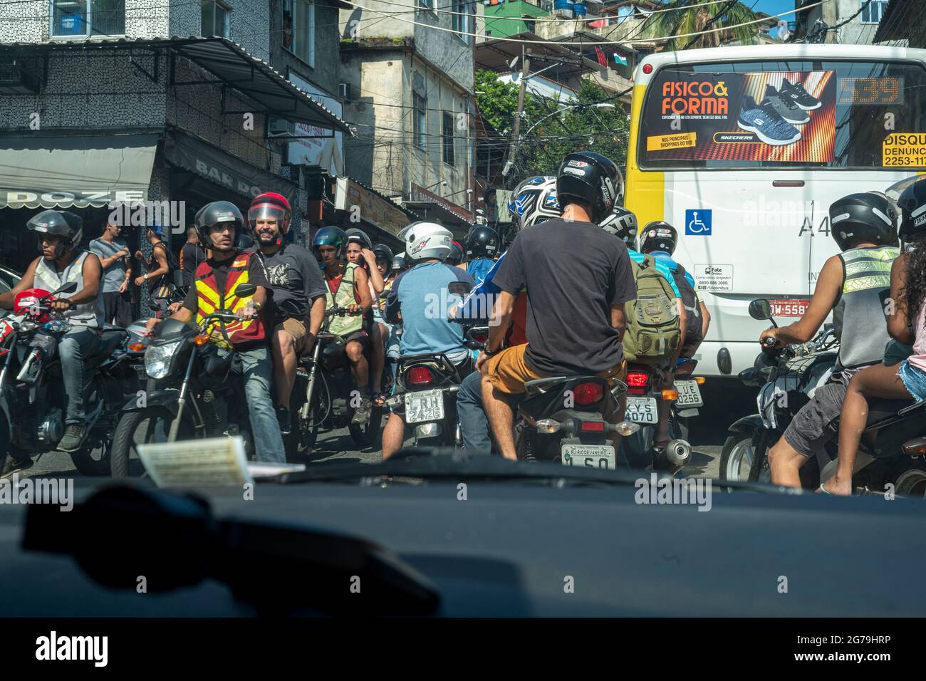 Una vista sulla strada che si affaccia su una strada con scooter e graffiti sulla parete di un edificio a Rocinha favela, una città shanty o baraccopoli a Rio, Brasile, Sud America Foto Stock